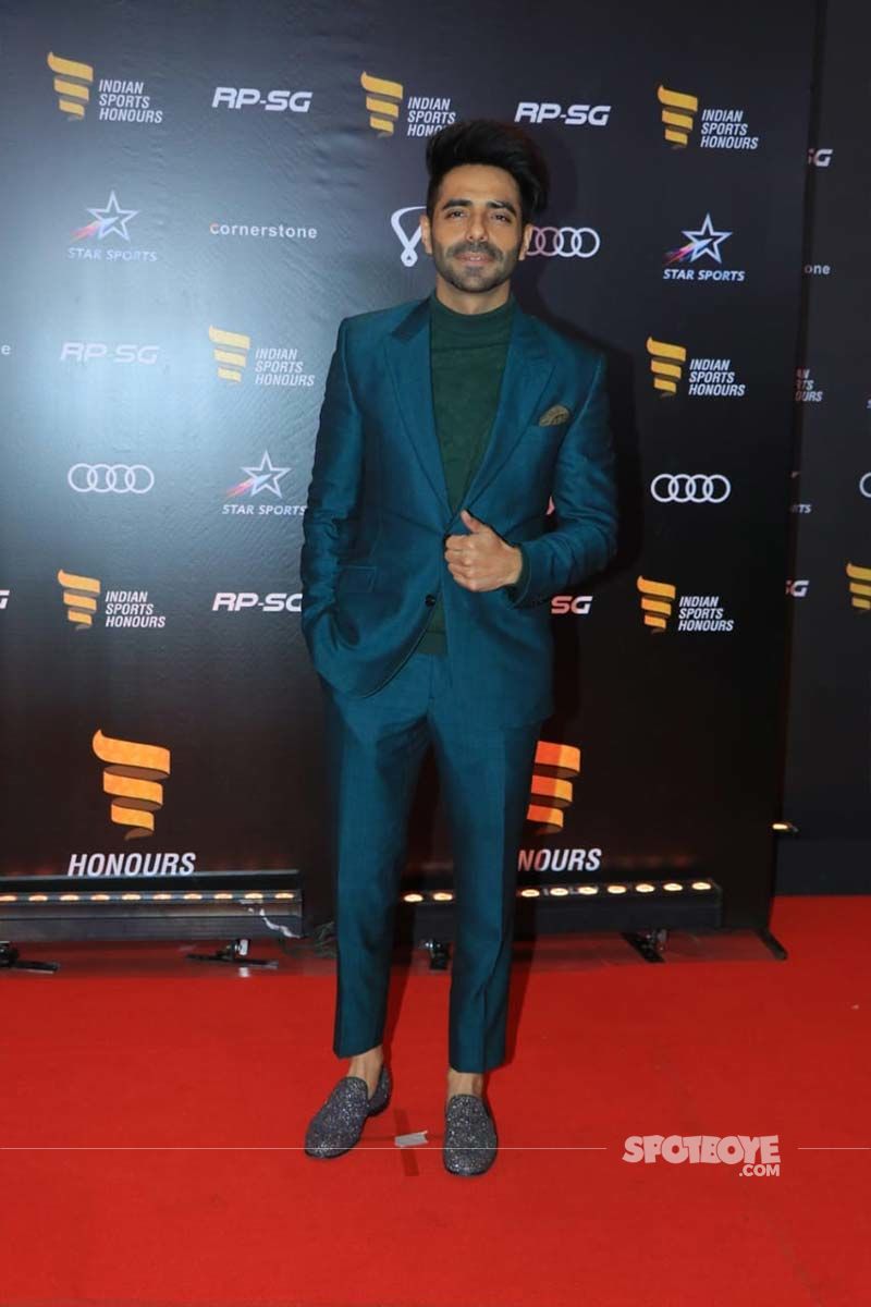 Aparshakti Khurana walks in wearing his best suit and smiling for the paparazzi [Image Source: Viral Bhayani]